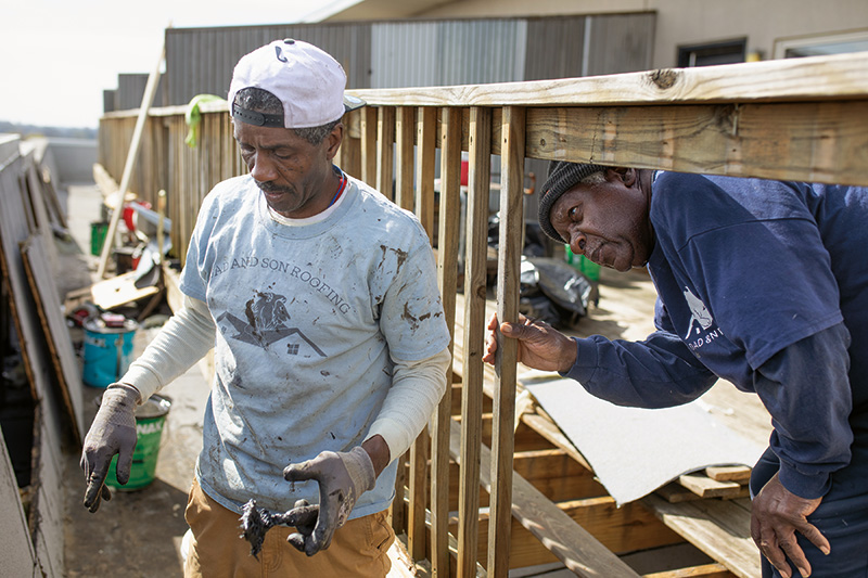 Two roofers mid-conversation on a construction site
