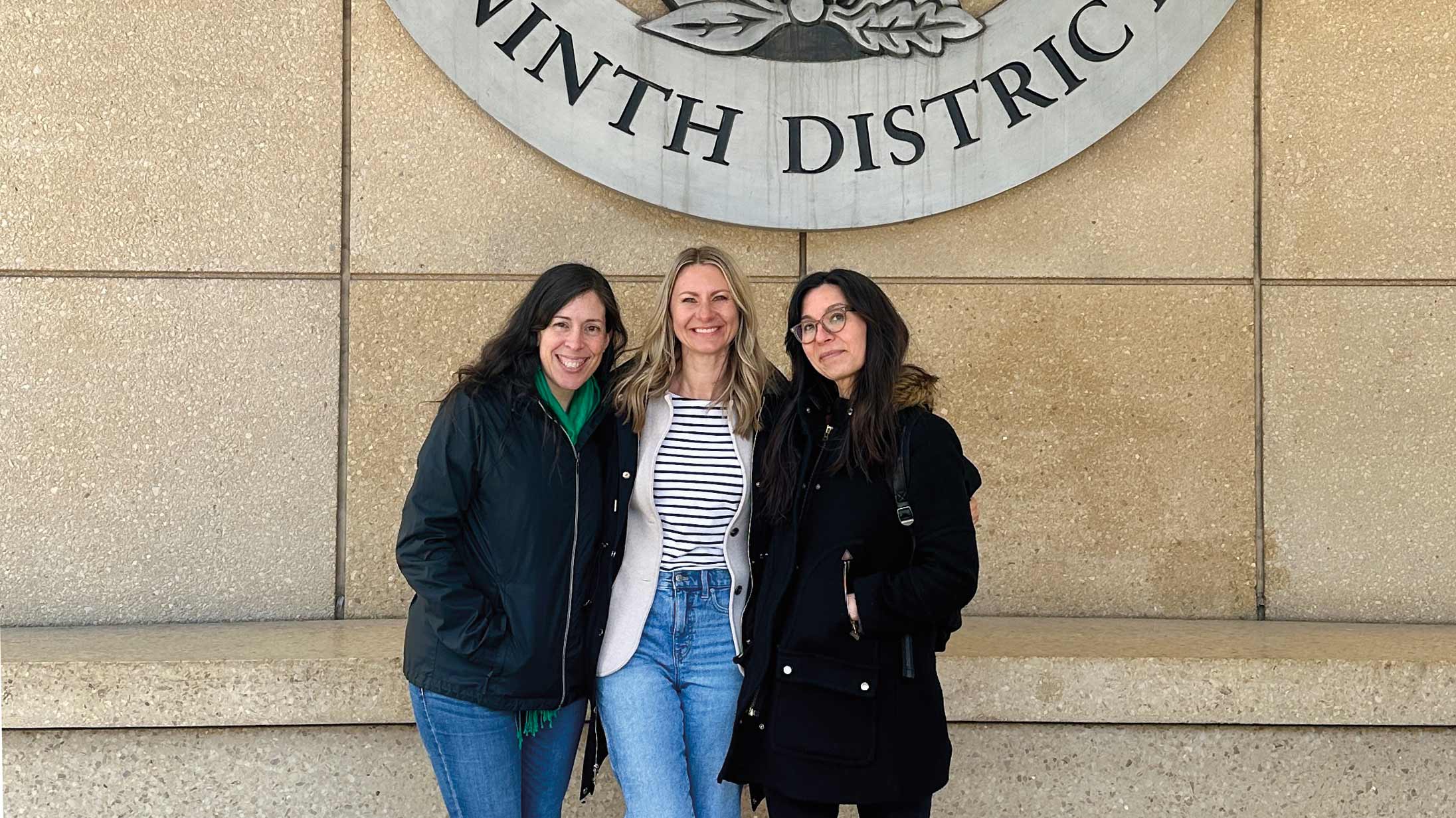 Photo of three scholars in front of Minneapolis Fed building