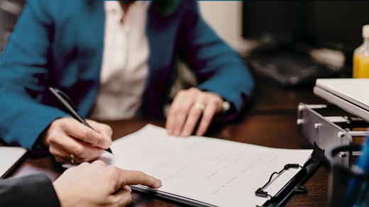 Closeup of two people reviewing and signing a legal document